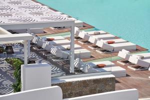 a row of lounge chairs sitting on top of a beach at Kouros Hotel & Suites in Mikonos