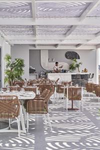 أجنحة وفندق كوروس في مدينة ميكونوس: مطعم بطاولات وكراسي وشخص في الخلفية