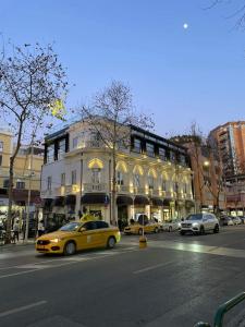 a yellow taxi cab driving down a city street at The Crown Boutique Hotel & SPA in Tirana