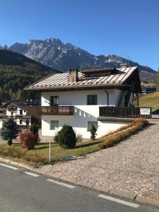 a white house with a roof on the side of a road at Affittacamere Iragidor in Cortina dʼAmpezzo