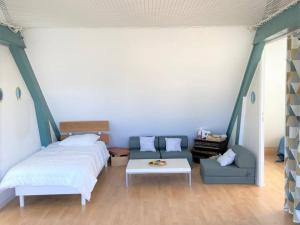 a bedroom with a bed and a couch and a table at Maison rénovée 3 étoiles à 150m de la plage, idéale pour familles avec espace enfants et Wifi - FR-1-481-116 in Bénodet