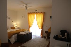 a bedroom with a bed and a window with yellow curtains at Casa das Palmas in Óbidos