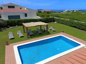 a swimming pool with chairs and a gazebo at VILLA VEGA RELAX EN EL PARAISO in Es Mercadal
