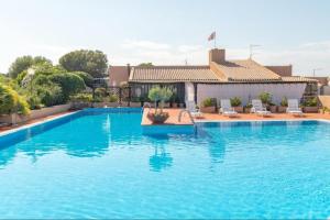 a large blue swimming pool with chairs and a building at Sardinia82 Sunsetplace in Palau