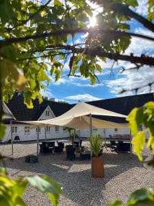 een wit gebouw met een tent en tafels en stoelen bij Gl. Brydegaard in Brydegård