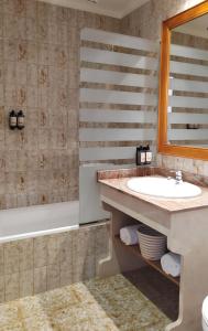 a bathroom with a sink and a tub and a mirror at Hotel Nou Can Guillem in Cala Figuera