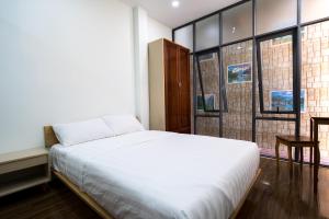 a bedroom with a white bed and large windows at Homestay TITO in Ho Chi Minh City