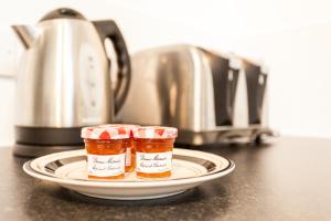 two jars of jam on a plate next to a toaster at Comfortable Contractor House Gatwick: sleeps 6+ in Ifield