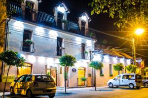 蒂米什瓦拉Hotel-Pensiunea Zefir的晚上，两辆汽车停在一栋建筑物前