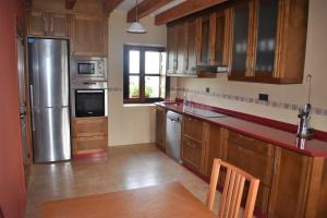 a kitchen with wooden cabinets and a stainless steel refrigerator at Casa Carmen y Mera in Ferroñes