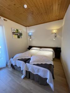 a bedroom with two beds and a wooden ceiling at Hotel Avet in La Coma i la Pedra