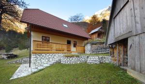 a house with a porch and a stone wall at Zadnjica Holiday House in Soča