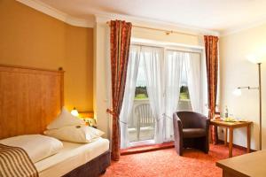 a bedroom with a bed and a window and a chair at Ringhotel Sonneck in Bad Wörishofen