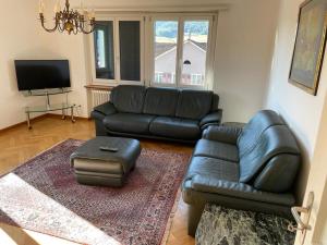 a living room with a black leather couch and a stool at Top Wohnen in Wangen