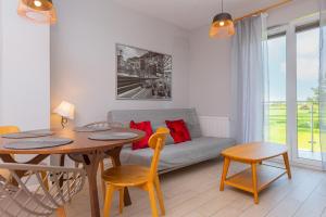 a living room with a table and a couch at Apartamenty Rodzinne Plater74 in Darłowo