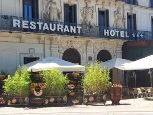 um hotel com guarda-sóis em frente a um edifício em Le Grand Hôtel Molière em Pézenas