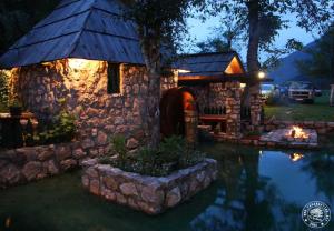 Casa de piedra con chimenea junto a un estanque en Rafting Camp Tara Center Tri Vodenice, en Bastasi