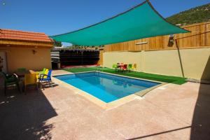 a swimming pool with a green umbrella next to a house at مزرعة سيلا خاصة للعائلات in Ajloun