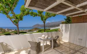 a patio with a table and chairs and the ocean at Fedra Guest House in Plakias