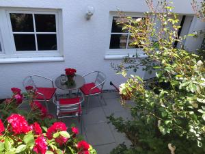 a patio with a table and chairs and red roses at Modernes Apartment mit Terrasse und Highspeed Internet zwischen Aalen und Schwäbisch Gmünd in Göggingen