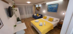 a small room with a yellow bed and a couch at Apartments & Rooms KARLA in Dramalj