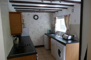 a kitchen with a sink and a washing machine at River Cottage in St Asaph