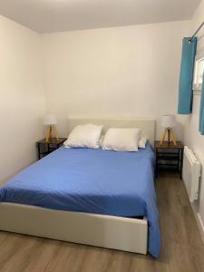 a bedroom with a bed with blue sheets and two lamps at L'Olivier in Saint-Mitre-les-Remparts