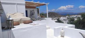 a white bedroom with a bed on a balcony at Prickly Pear House in Plaka Milou