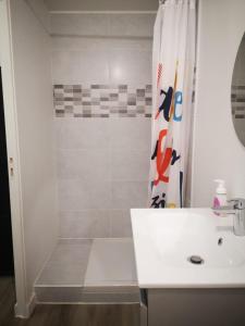 a white bathroom with a shower and a sink at L'Olivier in Saint-Mitre-les-Remparts