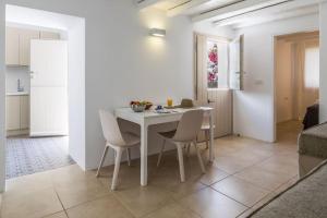a white dining room with a white table and chairs at Gazia Guesthouse Milos in Adamas