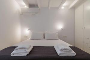 a white bedroom with a bed with towels on it at Gazia Guesthouse Milos in Adamas +6 photos