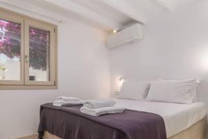 a white bedroom with a bed with towels on it at Gazia Guesthouse Milos in Adamas