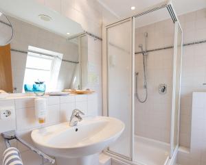 uma casa de banho com um lavatório e um chuveiro em Hotel Muschelgrund em Cuxhaven