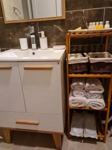 La salle de bains est pourvue d'un lavabo et d'une étagère avec des serviettes. dans l'établissement Apartments Zec, à Čanj