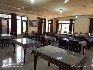- une salle à manger avec des tables, des chaises et des fenêtres dans l'établissement Hotel curio's All seasons, à Srinagar