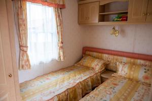 zwei Betten in einem kleinen Zimmer mit Fenster in der Unterkunft Domek na Skraju Lasu Kruklanki koło Giżycko Mazury in Kruklanki