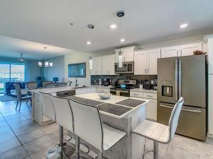 eine Küche mit weißen Schränken und eine Kücheninsel mit Stühlen in der Unterkunft Luxury Brand NEW 2 bedroom apt near DISNEY! in Kissimmee