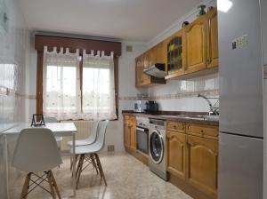 a kitchen with wooden cabinets and a table and a dishwasher at La Villa De Lore, Piso Completo Apto 6 Personas Con Garaje in Avilés