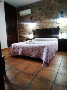 1 dormitorio con 1 cama en una pared de piedra en Apartamentos Rurales Tierras de Granadilla, en Zarza de Granadilla