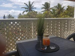 a table with two glasses of orange juice on a balcony at Superbe studio avec varangue à 150 m de la plage à la saline les bains in La Saline les Bains