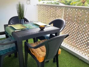 d'une table et de chaises noires sur le balcon. dans l'établissement Superbe studio avec varangue à 150 m de la plage à la saline les bains, à La Saline les Bains