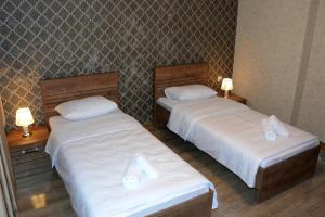 2 camas en una habitación de hotel con sábanas blancas en Tulpan Hotel, en Sheki