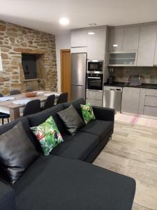 a living room with a black couch and a kitchen at Refúgio do Côa - Pure Countryside Experience in Pinhel +13 photos