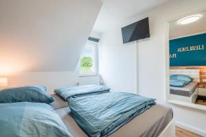 Duas camas num quarto com uma televisão na parede em Ferienhaus Steuerbord mit Kamin und Terrasse - 4 Sterne DTV-Klassifizierung em Carolinensiel