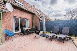 カロリーネンジールにあるFerienhaus Steuerbord mit Kamin und Terrasse - 4 Sterne DTV-Klassifizierungのパティオ(椅子、テーブル、フェンス付)