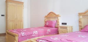 2 letti in una camera con lenzuola rosa di appartement boukidan ad Al-Ḥoseyma