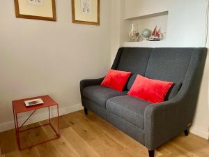 a gray couch with two red pillows in a living room at Les Petits Volets 3 appartements au choix in Antibes