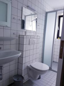 a white bathroom with a toilet and a sink at Strande, fast am Strand in Strande