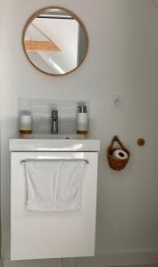 een badkamer met een witte wastafel en een spiegel bij Studio cosy avec coin jardin in Lancieux