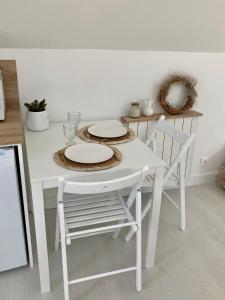 een witte tafel en stoelen met borden erop bij Studio cosy avec coin jardin in Lancieux